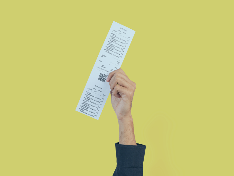 Fundo amarelo, mão de homem branco usando camisa preta segurando um cupom fiscal